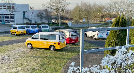 Campervans parked on a green lawn at the roadsurfer station in Bochum