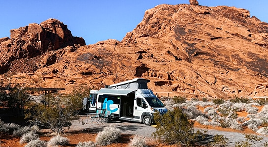 Campervan in the american outback in front of a red-stoned hill