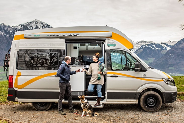 couple camping with a roadsufer sprinter van and their dog