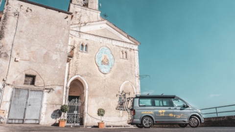 Grey Volkswagen camper van next to an Italian church