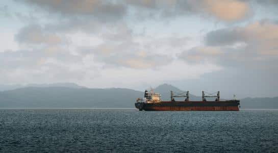 Large cargo ship sailing on the Columbia River near Astoria, Oregon under cloudy skies.