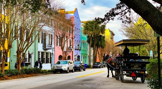 Colorful houses along Rainbow Row in Charleston, South Carolina, with a horse-drawn carriage passing through the historic district