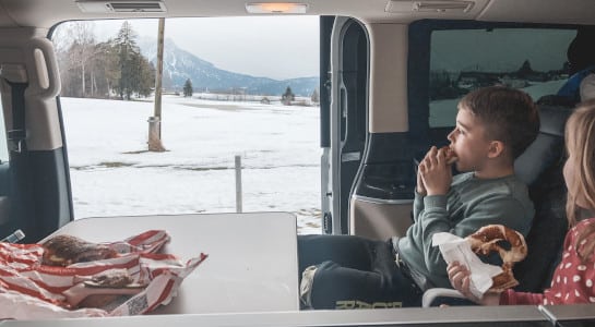 children eating in a camper van in snowy landscape