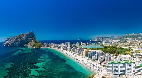 Panoramic view of Calpe on the Costa Blanca, with the Peñón de Ifach, turquoise Mediterranean waters, beaches and city skyline.