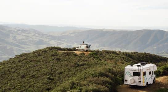 Class B and Class C RVs overlooking green mountain ranges from a high ridge