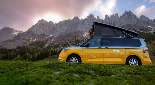 Class B RV rental parked in the mountains with a pop-top roof and a traveler enjoying the sunset view