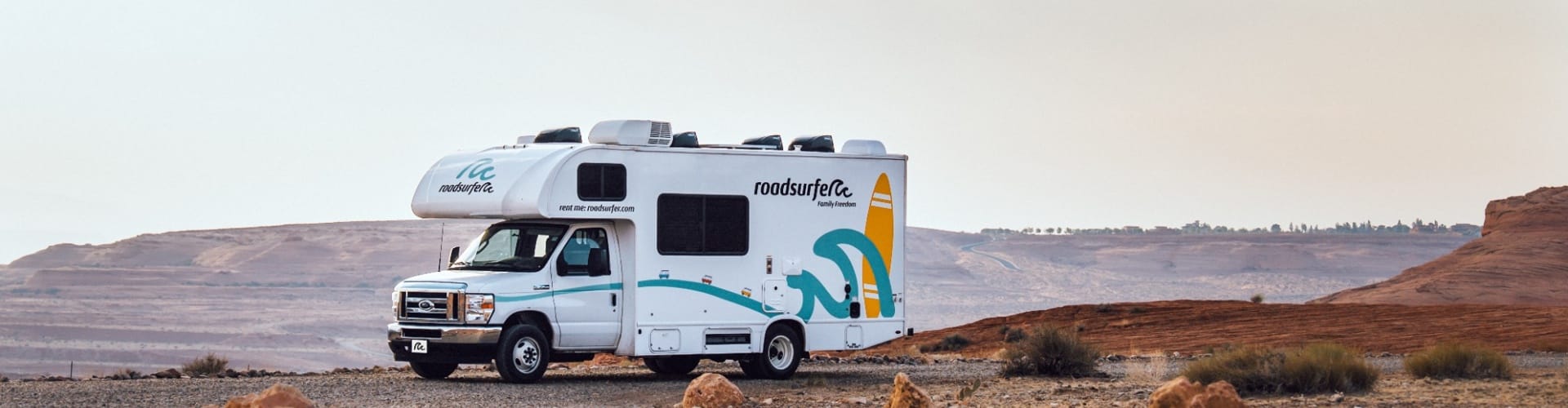 A white roadsurfer RV parked in a wide desert landscape, illustrating the difference between Class B and Class C RVs.