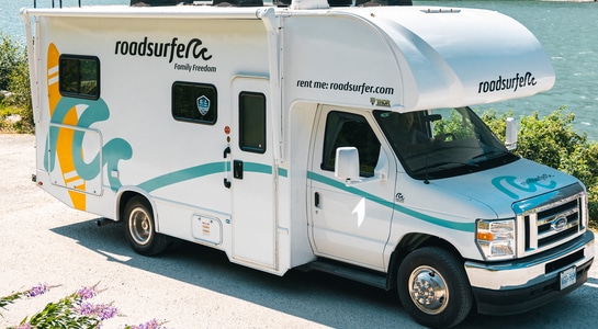 Class C RV parked alongside the riverside.