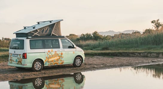 Colorful roadsurfer campervan parked by a lake