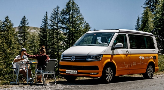 couple at picknick table next to yellow camper van