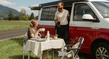 couple having breakfast outside of their red van