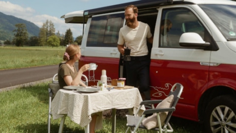 couple having breakfast outside of their red van
