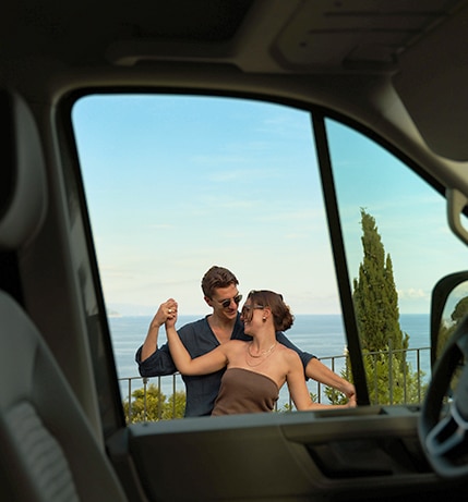 Happy couple hugging each other, captured through the window of a campervan