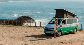 Couple in front of a campervan with ocean in the background