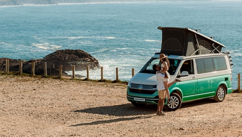 Couple in front of a campervan with ocean in the background