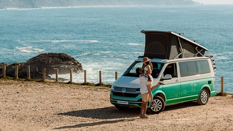 Couple in front of a campervan with ocean in the background