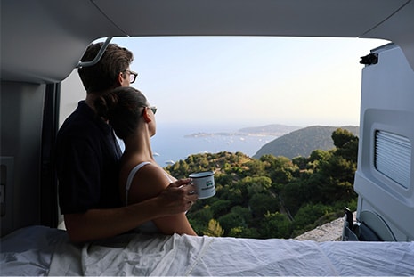 Couple looking from campervan to french mediterranean coast
