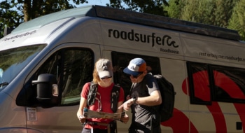 Couple planning route with a map in front of a camper.