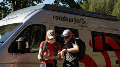 Couple planning route with a map in front of a camper.