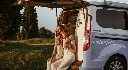 couple sits in the back of a campervan