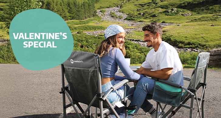 Couple sitting together on camping chairs enjoying the sunshine