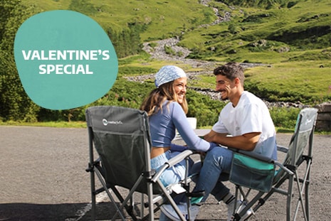 Couple sitting together on camping chairs enjoying the sunshine