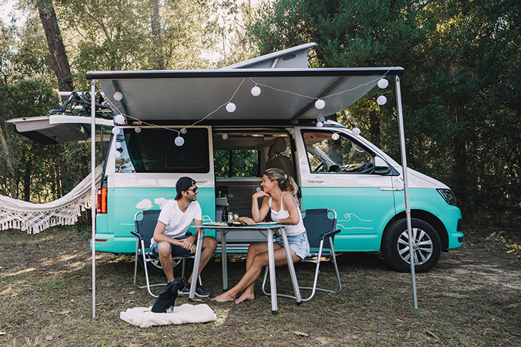 Couple sitting at a table in front of their vw california campervan