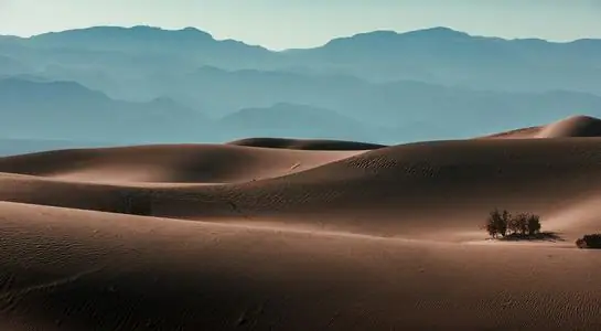 Rolling sand dunes with mountain backdrop in Death Valley National Park