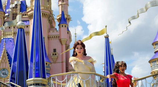 Disney princesses waving from a parade float in front of the Cinderella Castle at Disney World