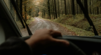 Driver's view of driving a camper through a rainy forest.