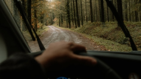Driver's view of driving a camper through a rainy forest.