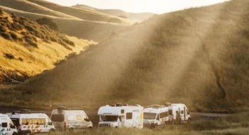 A lineup of RVs parked in golden California hills at sunset, illustrating different rv classes ready for travel.