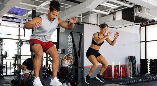 Two people doing box jumps during a group workout in an F45 Training studio