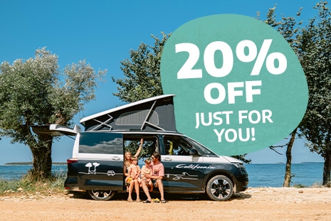 Family of four sitting in the doorway of a campervan