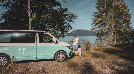 family with a camper van by the lake