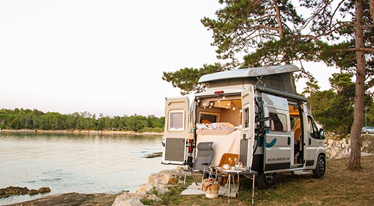 Fiat Ducato campervan standing with open doors at a lakeside