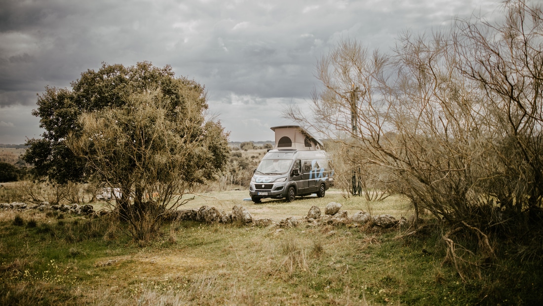 Fiat ducato campervan with open roof on a field with cloudy sky