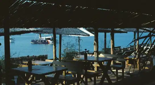 Wooden tables under thatched umbrellas overlooking turquoise water and anchored boats in the Florida Keys.