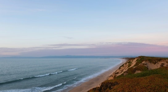 Peaceful empty shoreline and rolling dunes at sunset, showcasing the wild beauty of beaches in California.