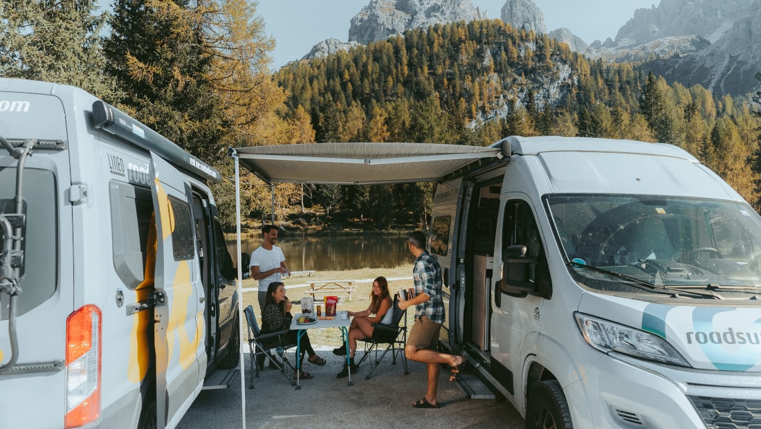 friends at camping table between two motorhomes