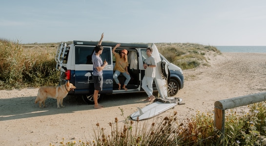 Some friends staying with a camper at the beach and having fun