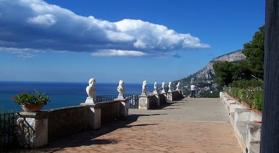 Garden terrace with small statues alongside the fence with view of the sea.