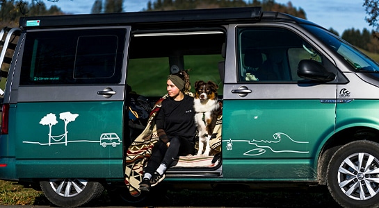 girl and dog with a blanket sitting inside a camper van