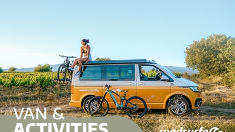 girl, campervan and two bikes in a summer landscape