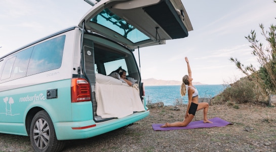 girl doing yoga next to a campervan at the coast