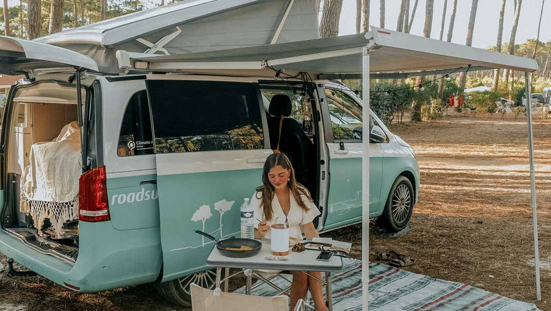 girl having lunch in front of a campervan