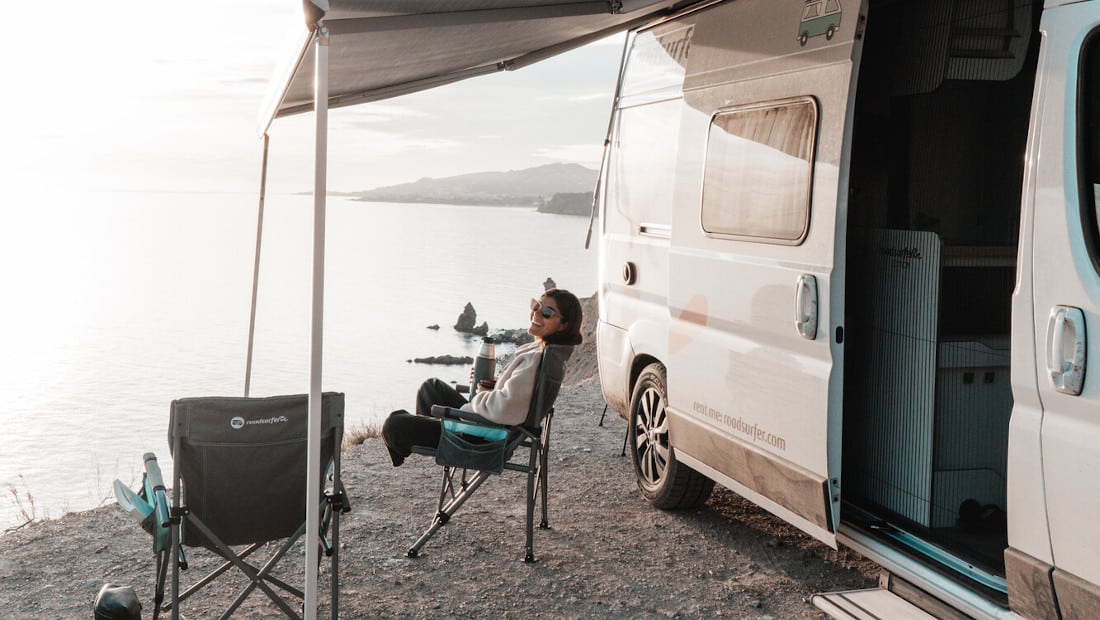 girl in a camping chair next to a motorhome