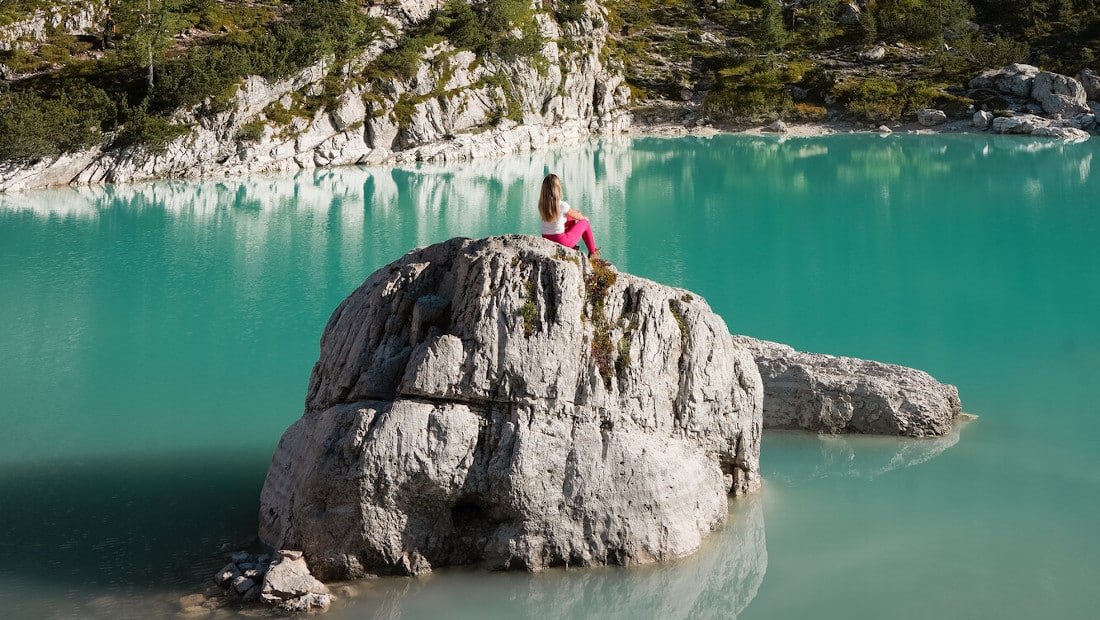 girl sits on a rock in a lake