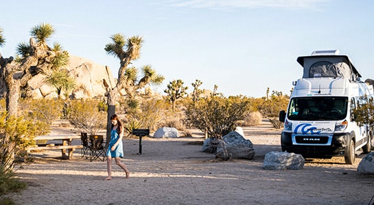 Girl in a dress walks across the campsite in the usa next to yoshua trees