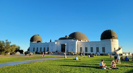 People relaxing on the lawn in front of Griffith Observatory under a clear blue sky—things to do in Southern California with kids.